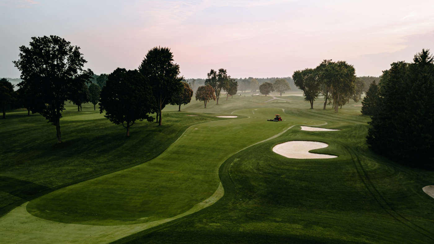 A quiet fairway at dawn under a pale pink sky