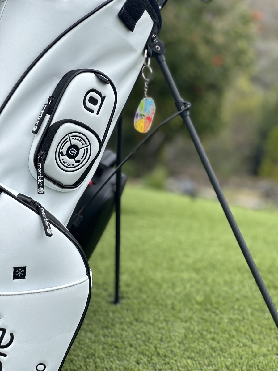 Close-up of the embroidered Marble crest ball pocket with branded metal zipper pulls